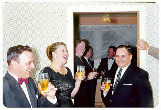 1950s / 1960s vintage photo of a 1950s / 1960s cocktail party featuring men and women holding glasses of drinks. 