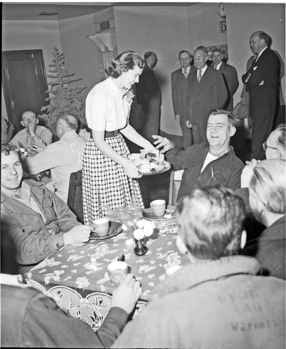 1950s vintage christmas party photo of a woman passing out desserts to the men at the office. 