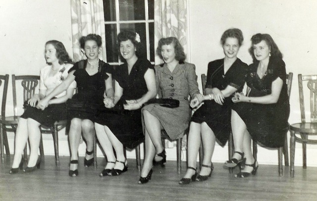 1940s vintage photo of women sitting down at a dance in 1940s dresses, 1940s shoes and 1940s hairstyles. 