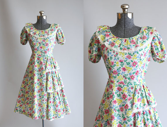 1940s fashion: 1940s Ethel Lou Jrs cotton dress features a colorful floral print. Ruffle detailing with eyelet trim at neckline and front skirt. Metal zipper up side of dress